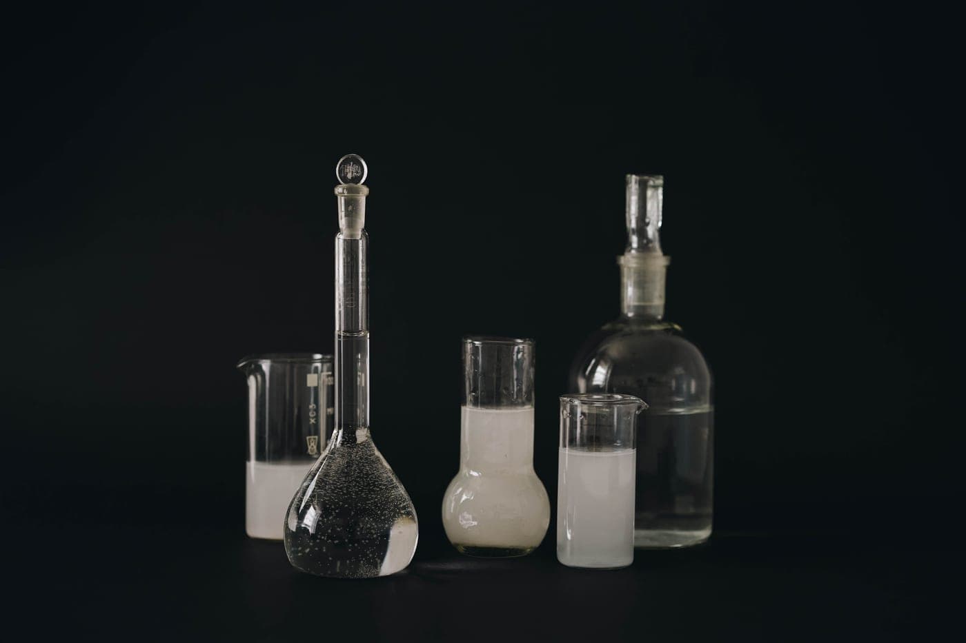 Glass laboratory vessels holding clear liquid under cool directional light