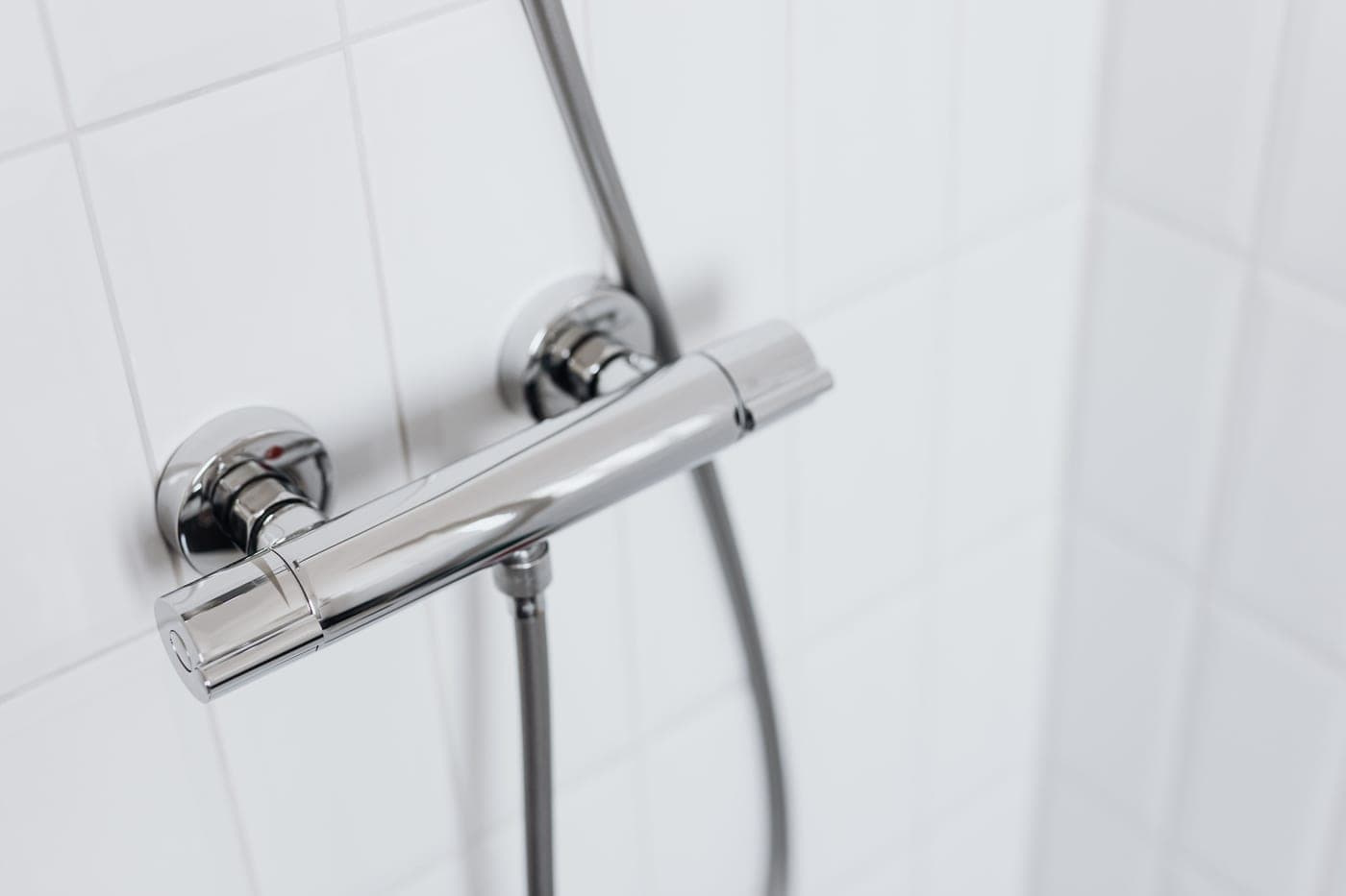 A row of chrome shower fittings on a plain surface under hard directional light