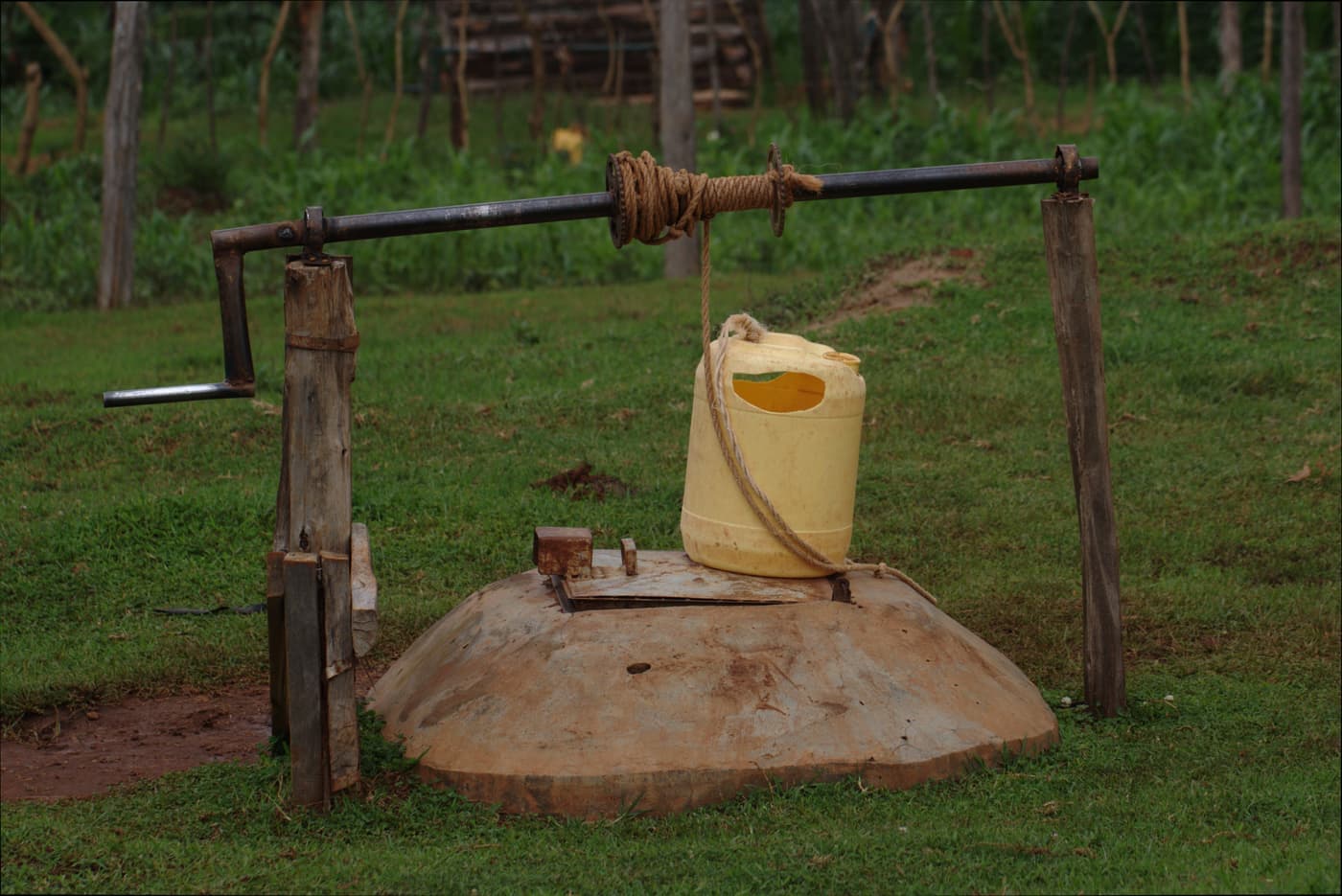A rural wellhead and pipework against bare ground under hard light