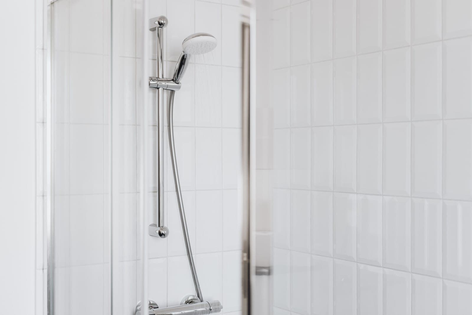 Two chrome shower fixtures side by side against a tiled wall