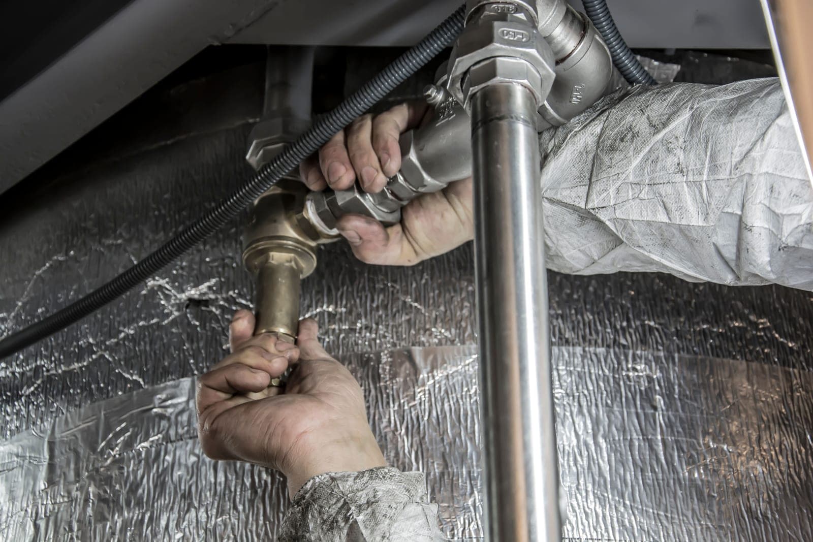 Hands fitting an inline filter body to a shower arm with a wrench