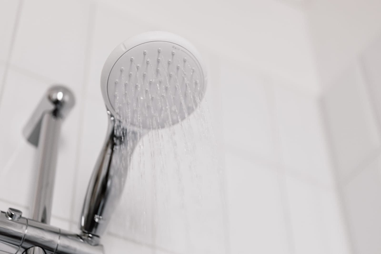 Chrome shower head photographed against a plain wall in hard directional light